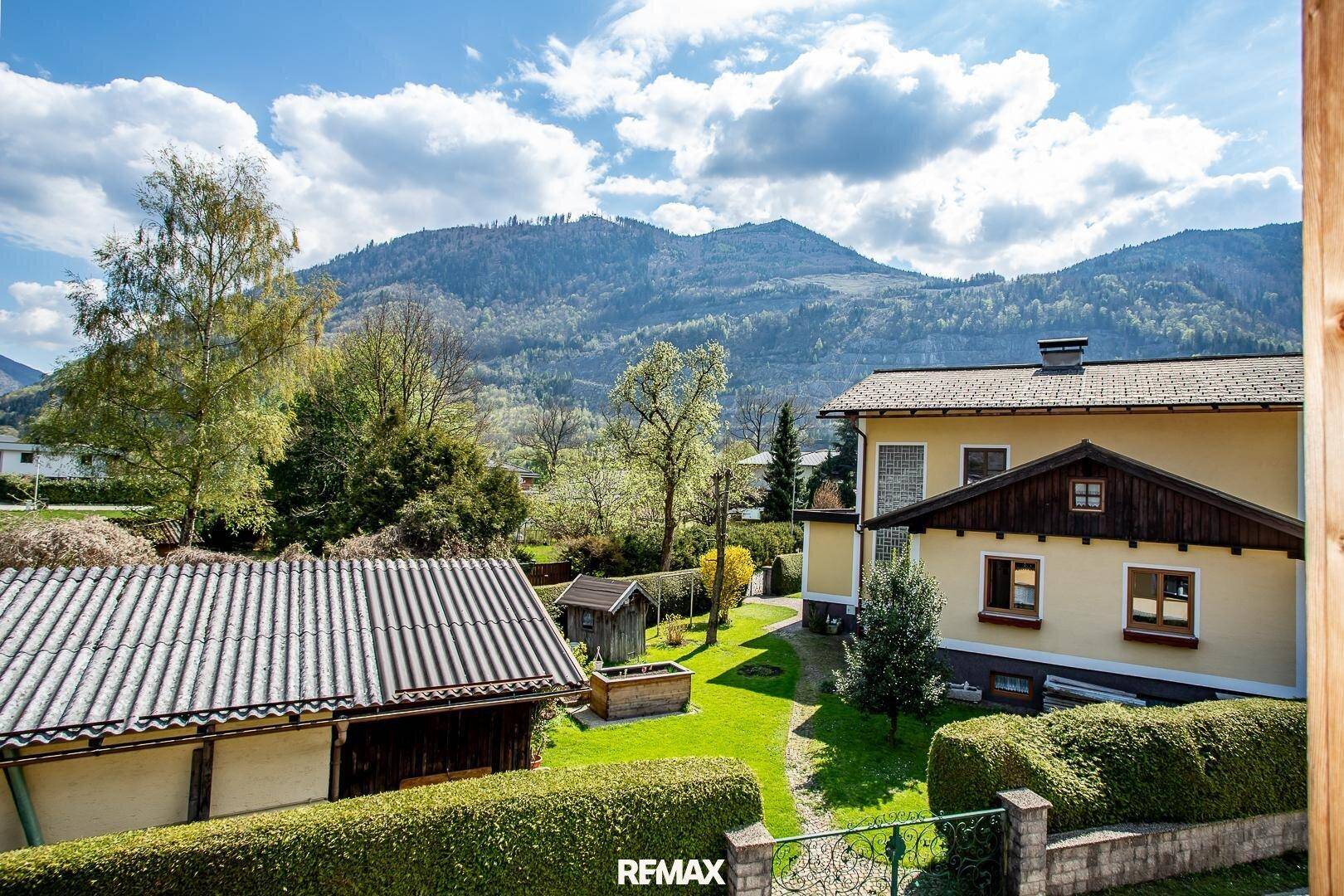 Weitläufiger Blick auf die grüne Umgebung, Berge und das Nachbarhaus mit Garten.