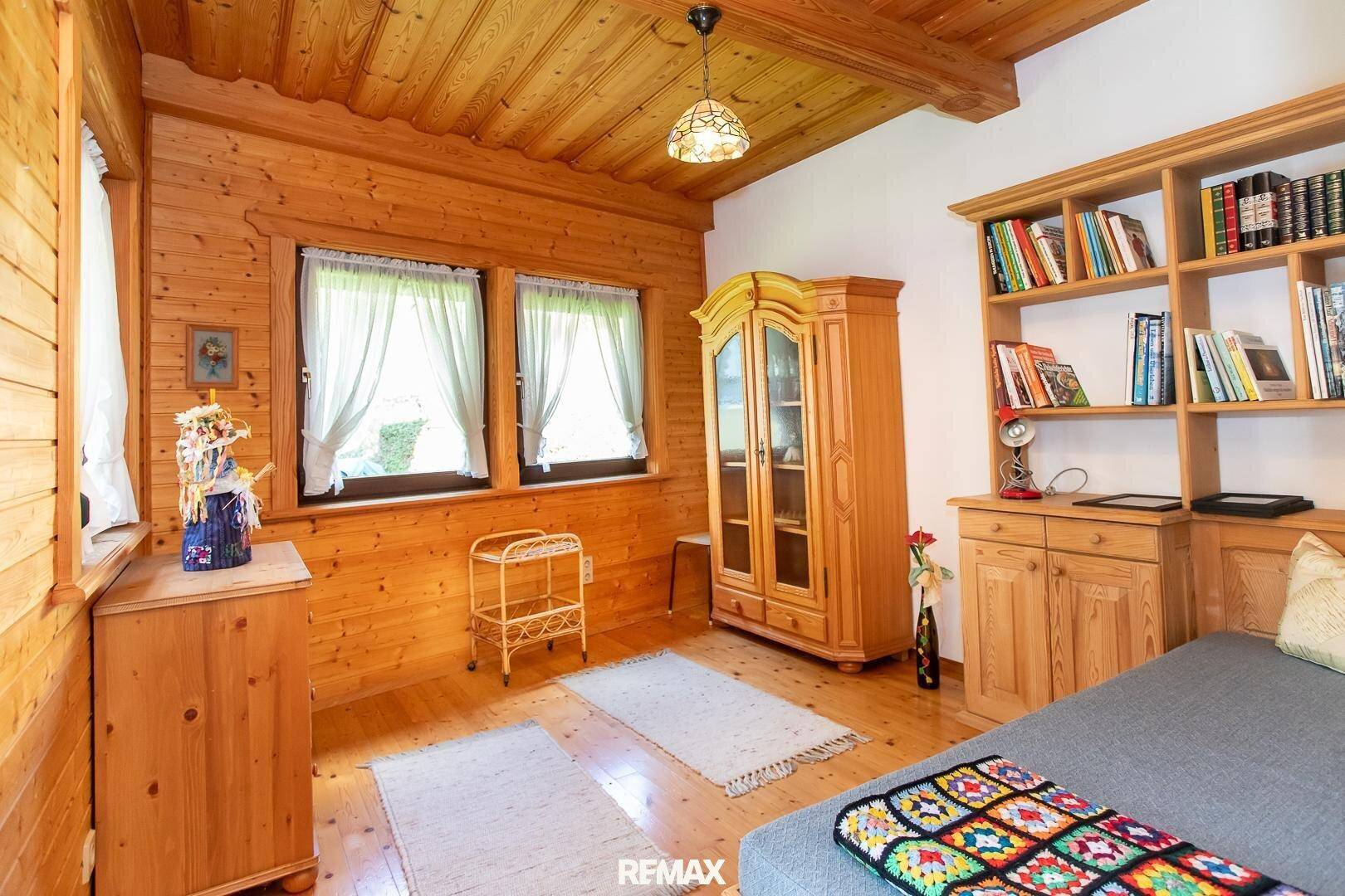 Schlafzimmer im Landhausstil mit Holzvertäfelung, Holzboden und Bücherregal.