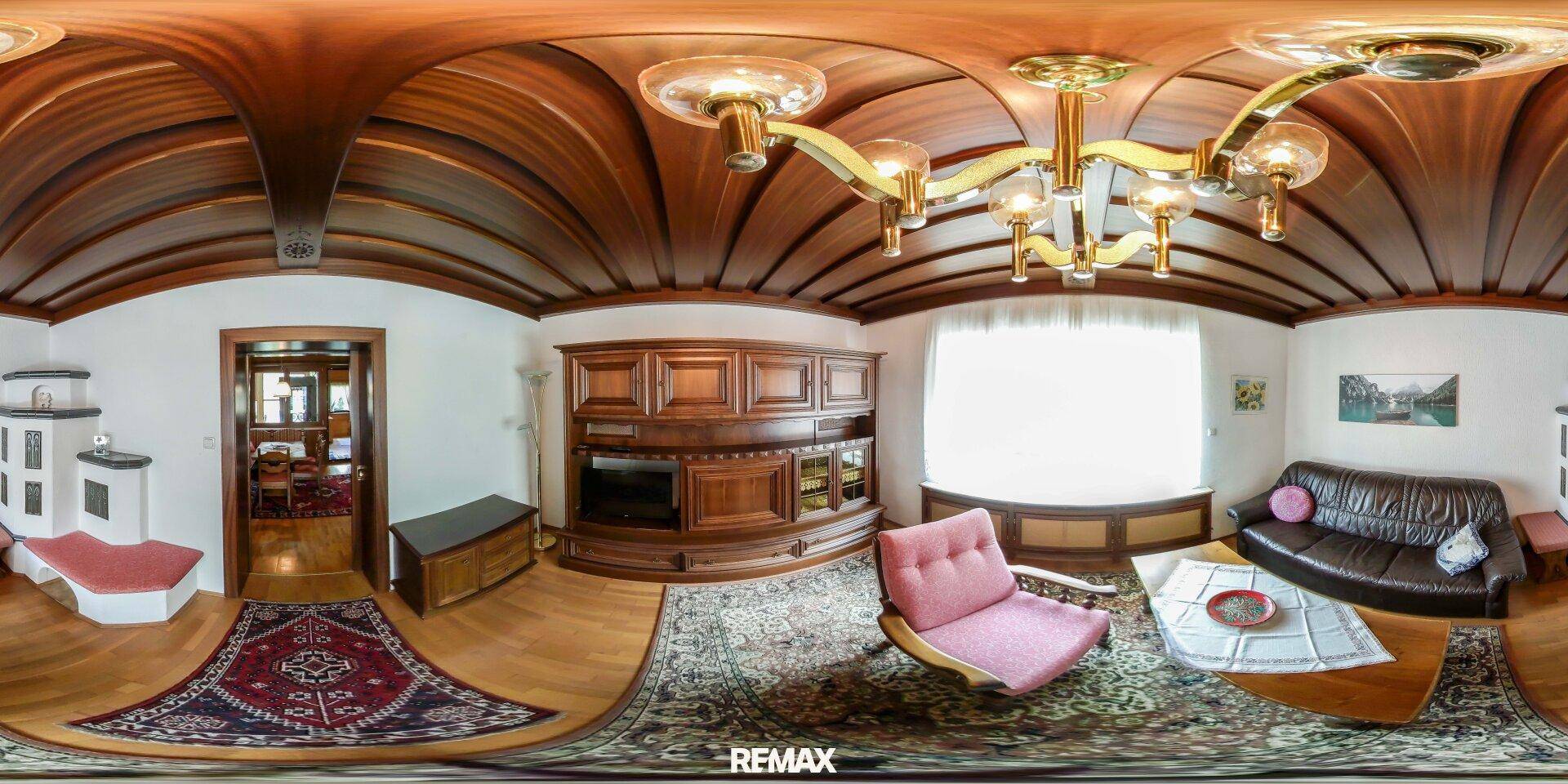 Traditionelles Wohnzimmer mit Holzbalkendecke, Kachelofen, Holzboden und klassischer Einrichtung.