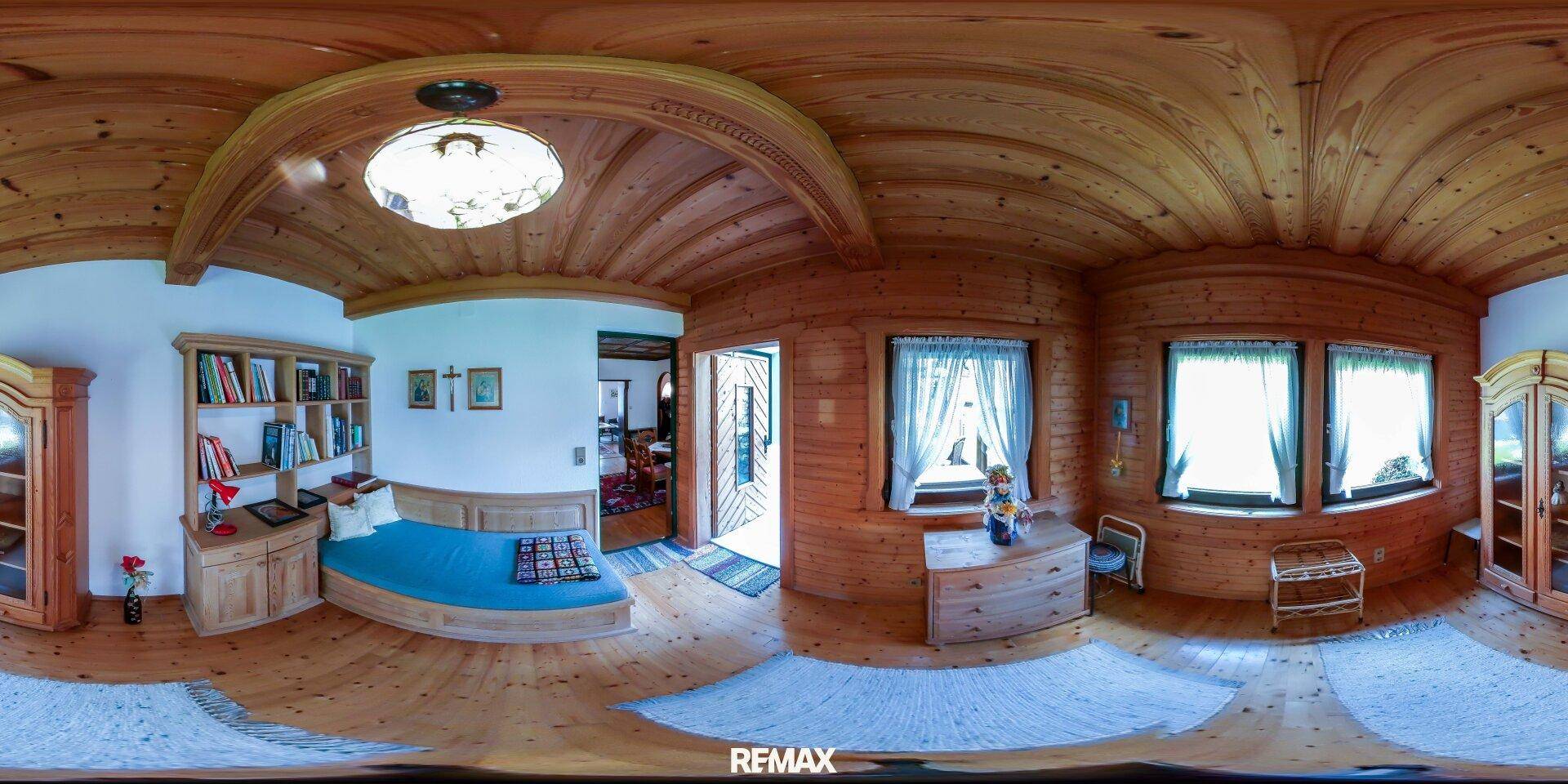 Gemütliches Wohnzimmer im alpinen Stil mit viel Holz, gewölbter Decke und hellen Fenstern.