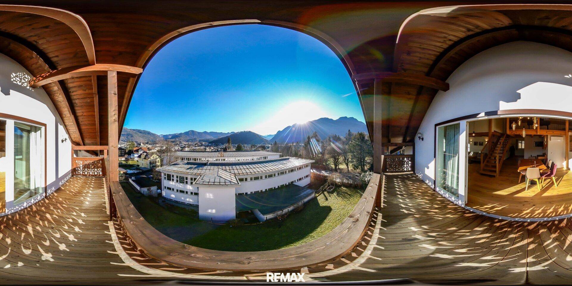Geräumiger Holzbalkon mit traditionellem Geländer und weitem Blick auf die Berge und die umliegende Landschaft.