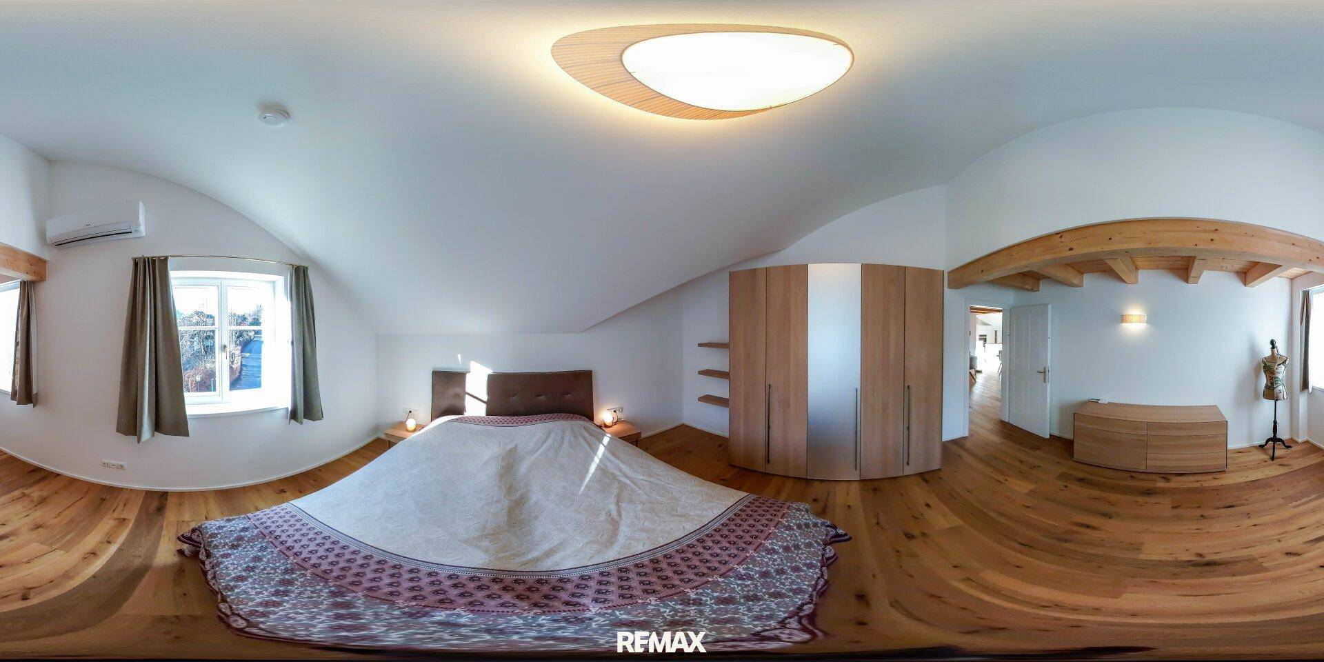 Helles Schlafzimmer mit Holzboden, Dachschrägen und einem großen Einbauschrank für viel Stauraum.
