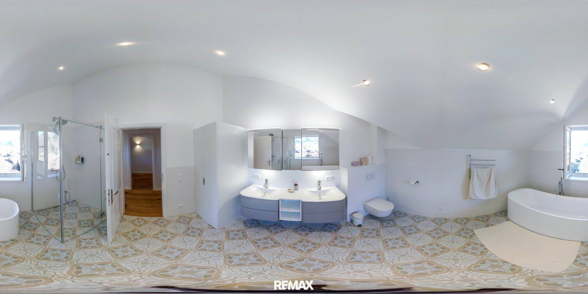 Modernes Badezimmer mit gemusterten Fliesen, Doppelwaschbecken, begehbarer Dusche und freistehender Badewanne.
