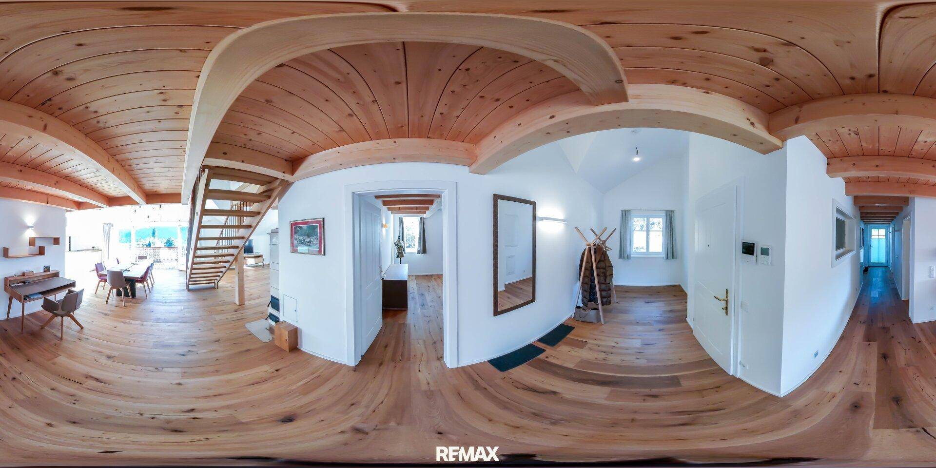 Heller Eingangsbereich mit Holztreppe, Holzboden und sichtbaren Deckenbalken, der zu den oberen Etagen führt.