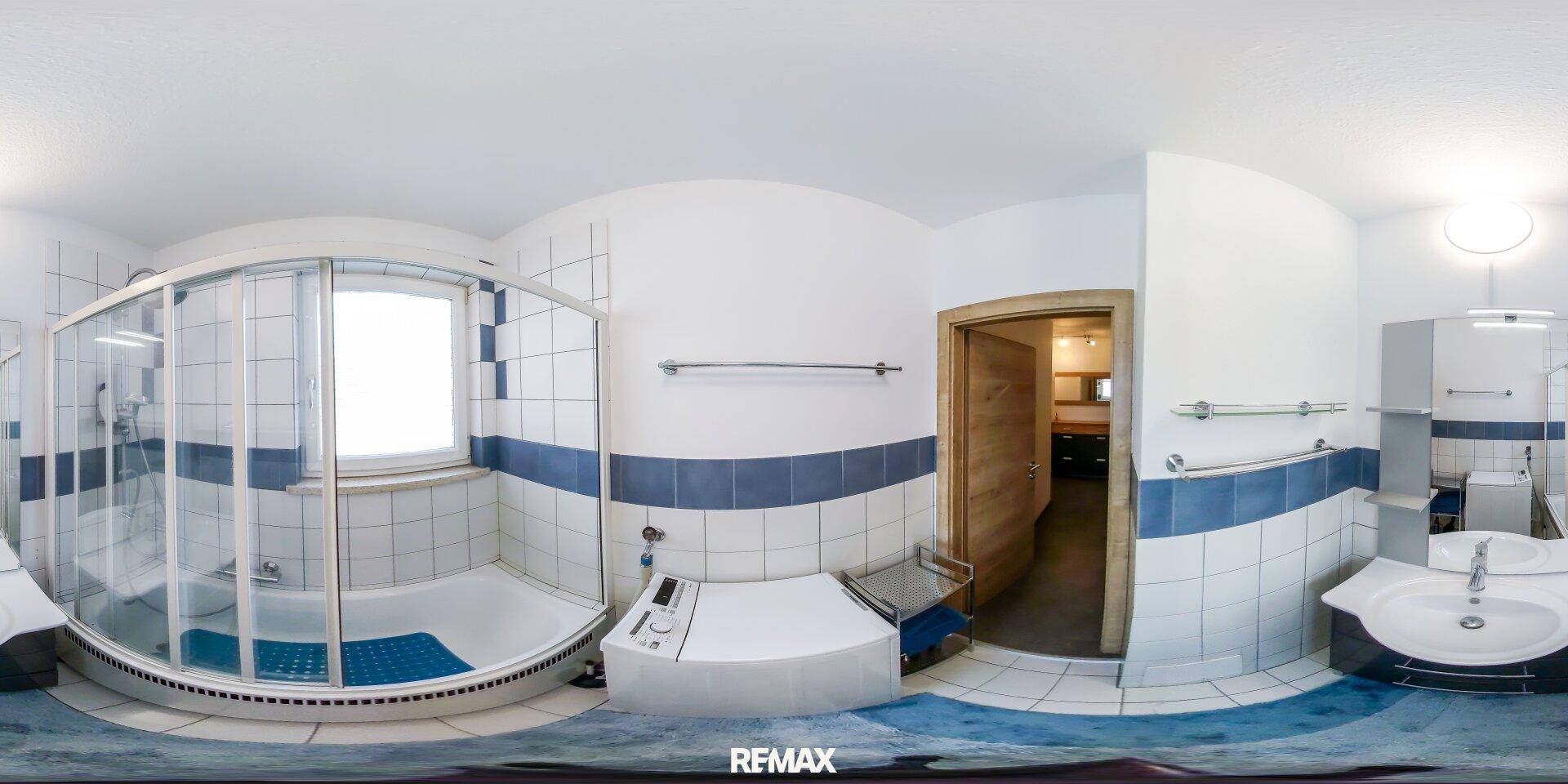 Helles Badezimmer mit Duschkabine, Waschbecken und WC, ausgestattet mit blauen und weißen Fliesen.