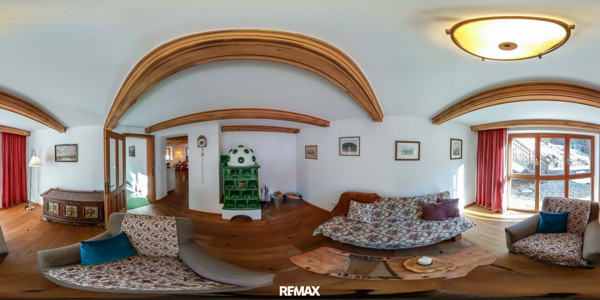 Gemütliches Wohnzimmer im alpinen Stil mit Kachelofen, Holzbalken und bequemen Sofas.