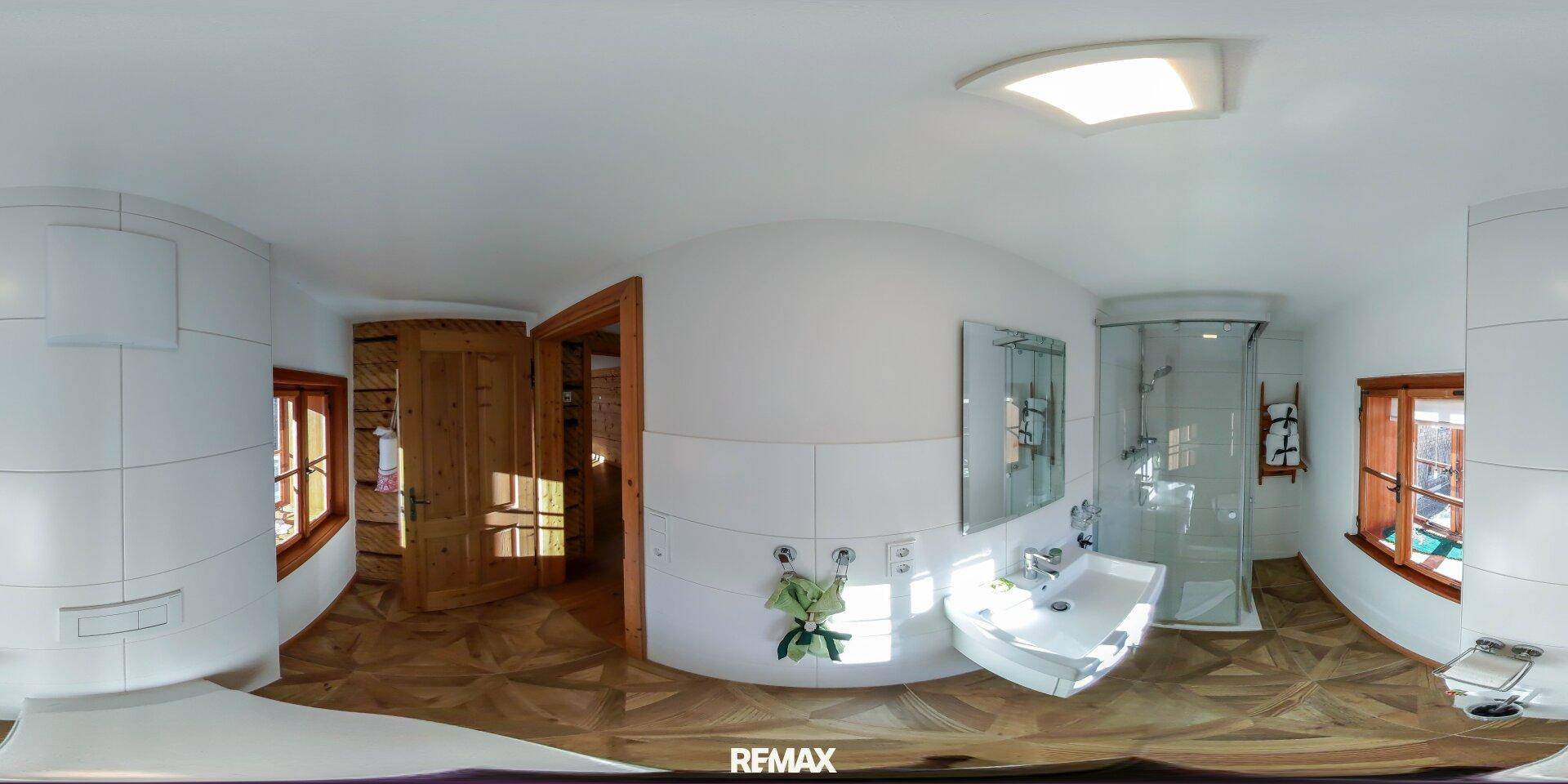 Helles Badezimmer mit weiß gefliesten Wänden, Dusche und Holzfenstern für natürliches Licht.