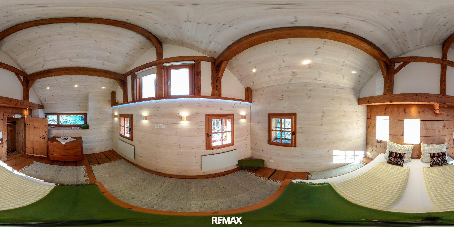Helles Schlafzimmer mit weiß getäfelten Wänden, Holzbalken und mehreren Fenstern.