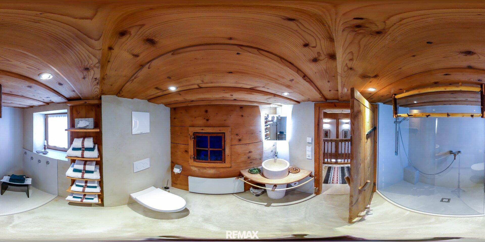 Badezimmer mit Holzwänden, modernem Waschbecken und Duschbereich in warmen Tönen.