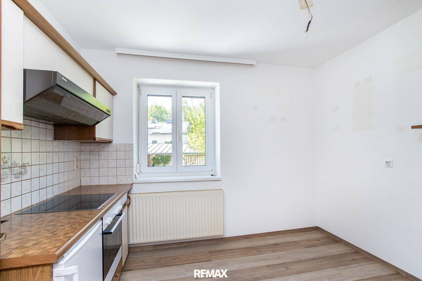 Funktionale Küche mit Einbauschränken, Kochfeld, Backofen und Fenster.