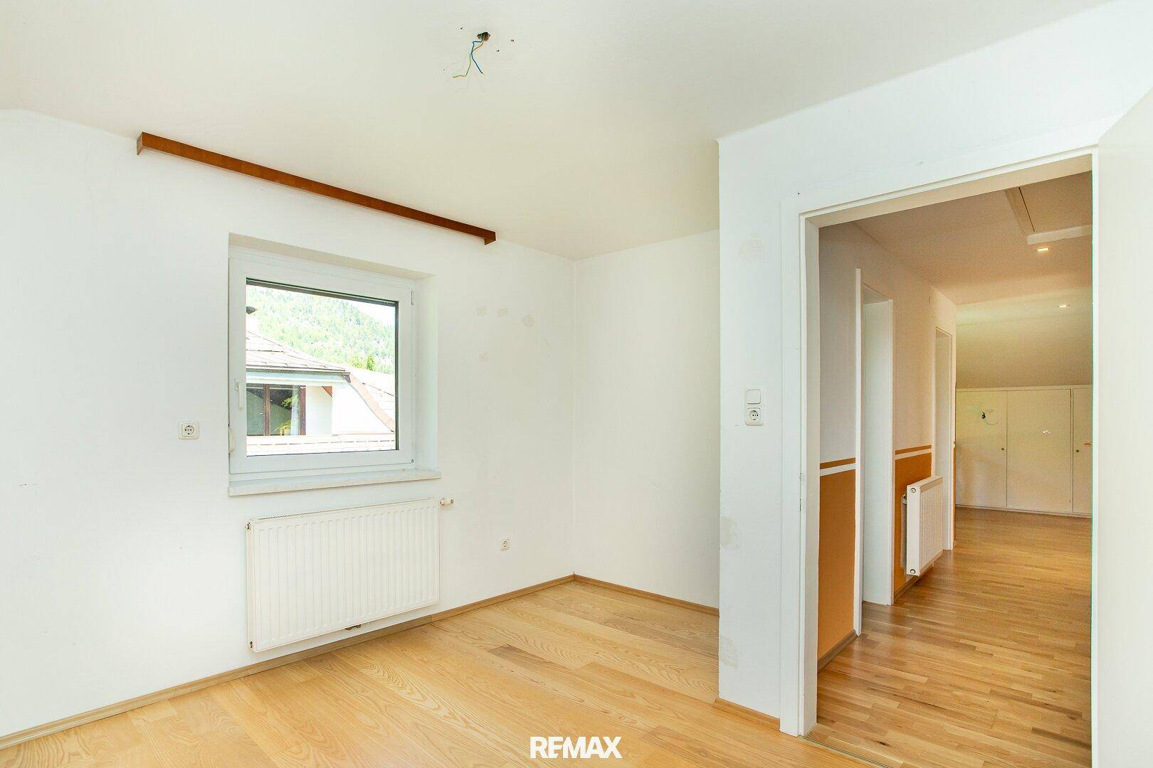 Heller Flur mit Holzboden und Fenster, der zu weiteren Räumen führt.