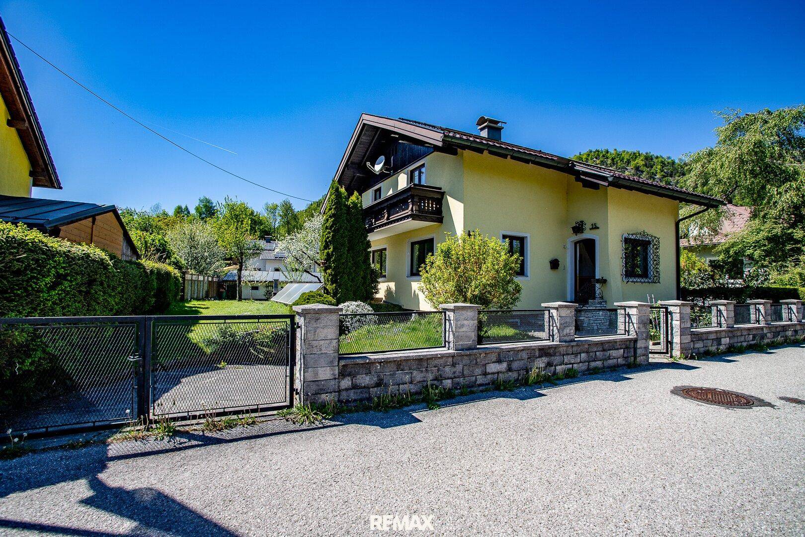 Ansicht des Einfamilienhauses von der Straße mit Vorgarten und Zaun.