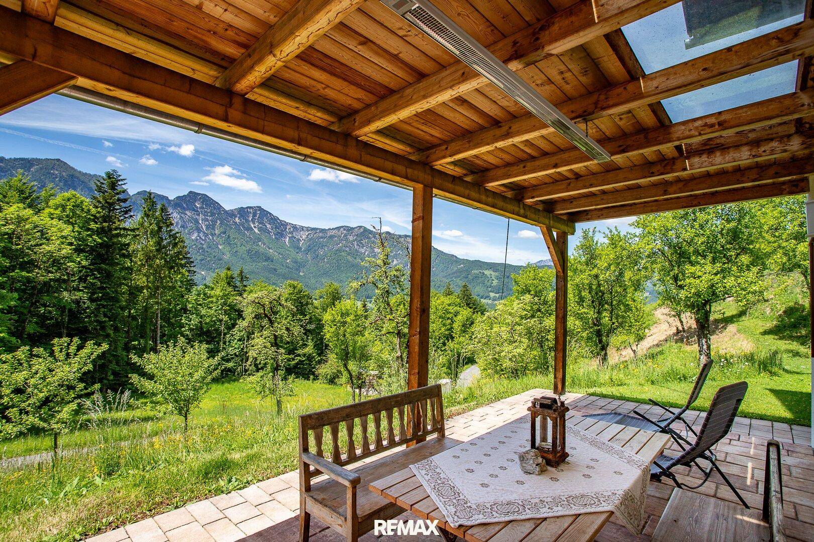 Überdachte Holzterrasse mit Sitzgelegenheiten und atemberaubendem Bergblick in die Natur.