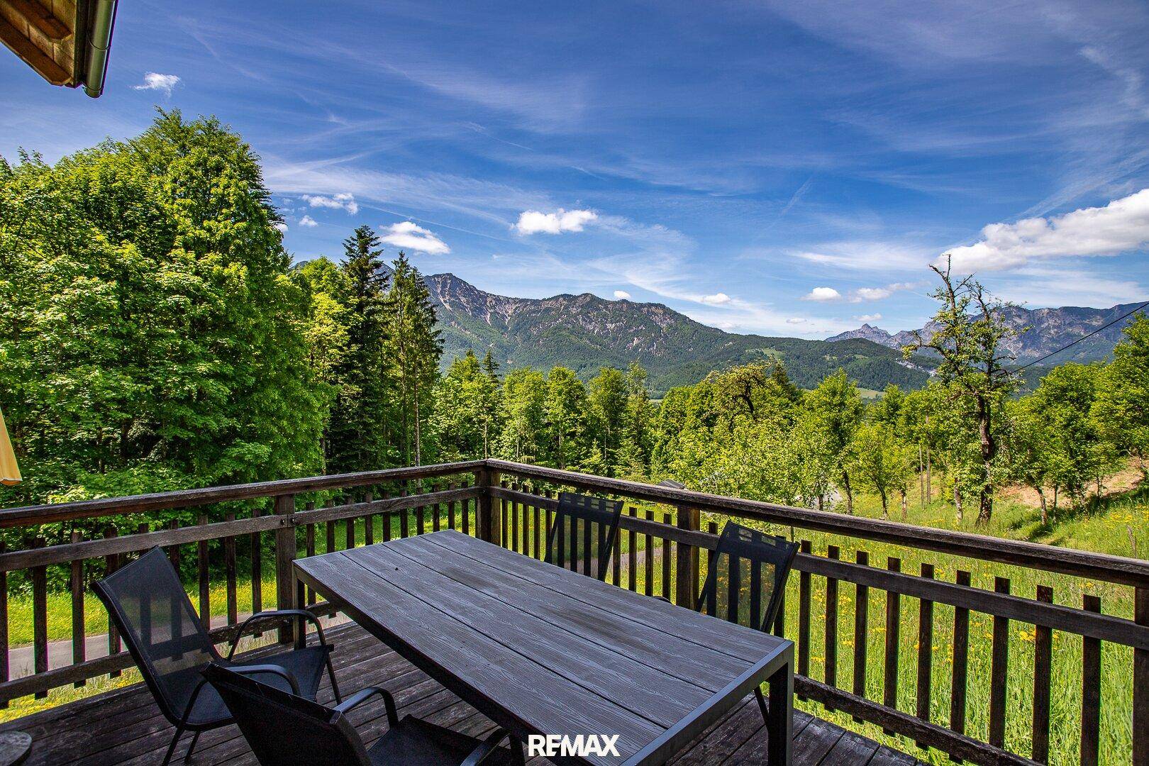 Geräumiger Holzbalkon mit Esstisch und Stühlen, bietet einen atemberaubenden Bergblick.