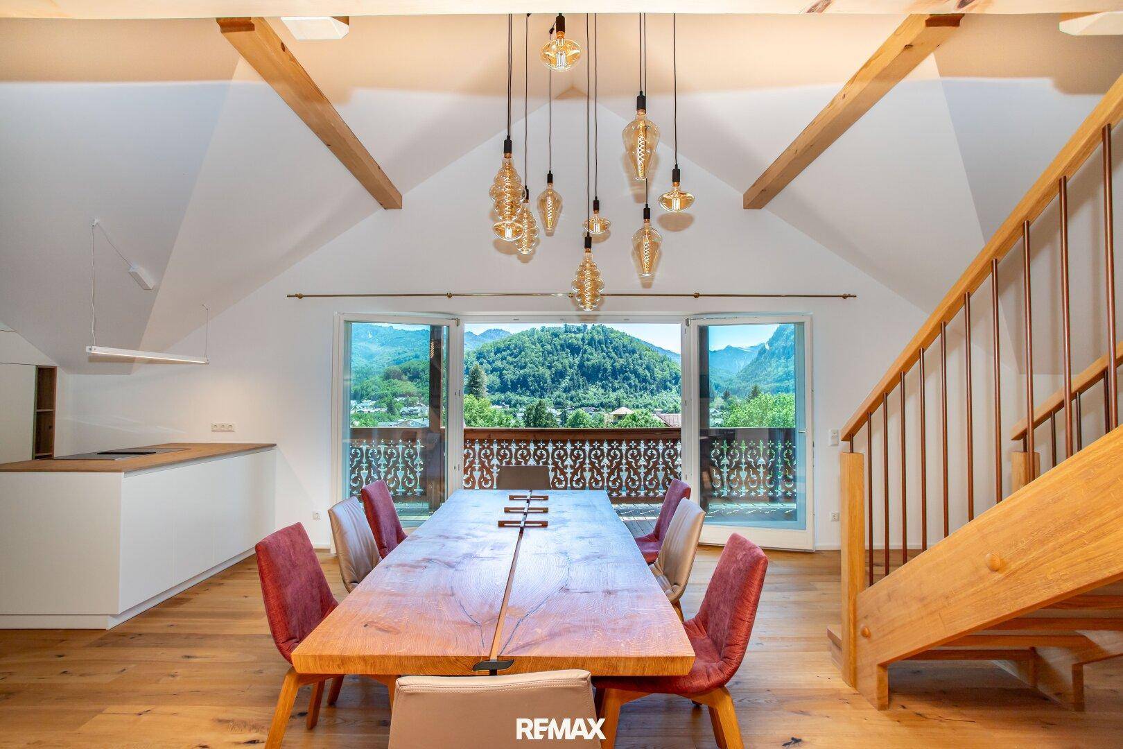 Heller Essbereich mit Holztisch, modernen Stühlen und Zugang zu einem Balkon mit Bergblick.