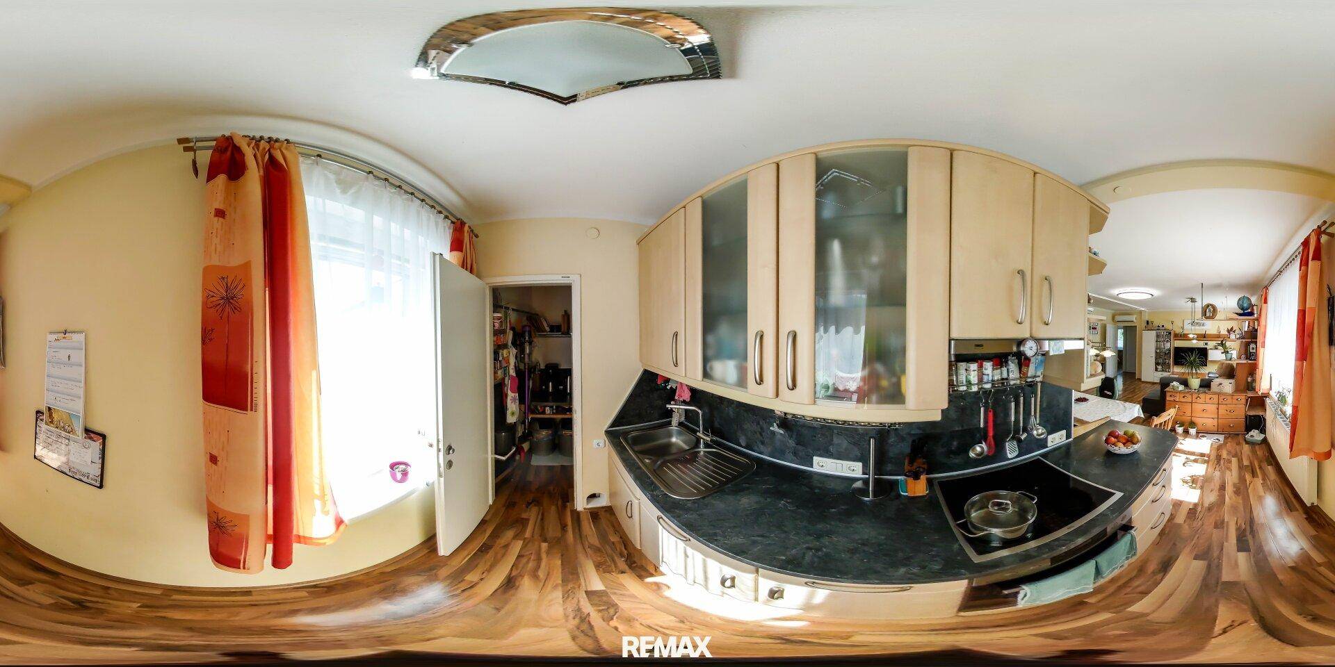 Panoramaansicht der funktionalen Küche mit hellen Holzschränken und dunkler Arbeitsplatte.