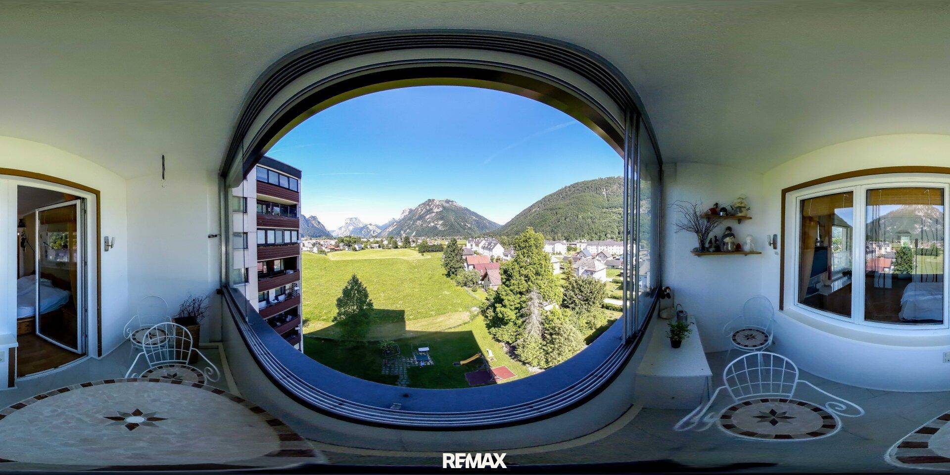 Panoramaansicht der verglasten Loggia mit atemberaubendem Bergblick und Sitzgelegenheiten.