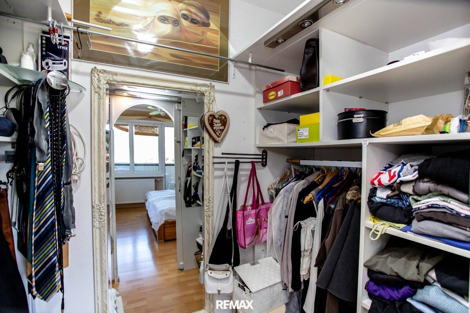 Praktischer begehbarer Kleiderschrank mit viel Stauraum und Spiegel, angrenzend an das Schlafzimmer.
