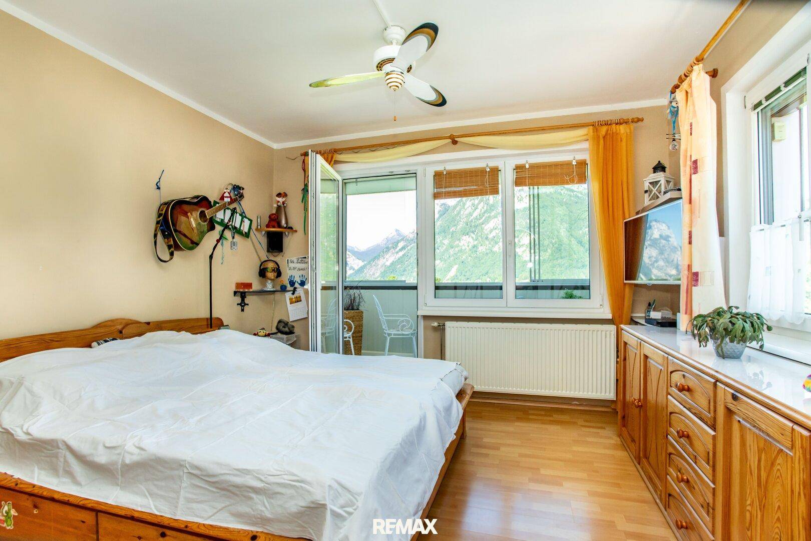 Geräumiges Schlafzimmer mit Holzmöbeln, großem Fenster und Zugang zum Balkon mit Bergblick.