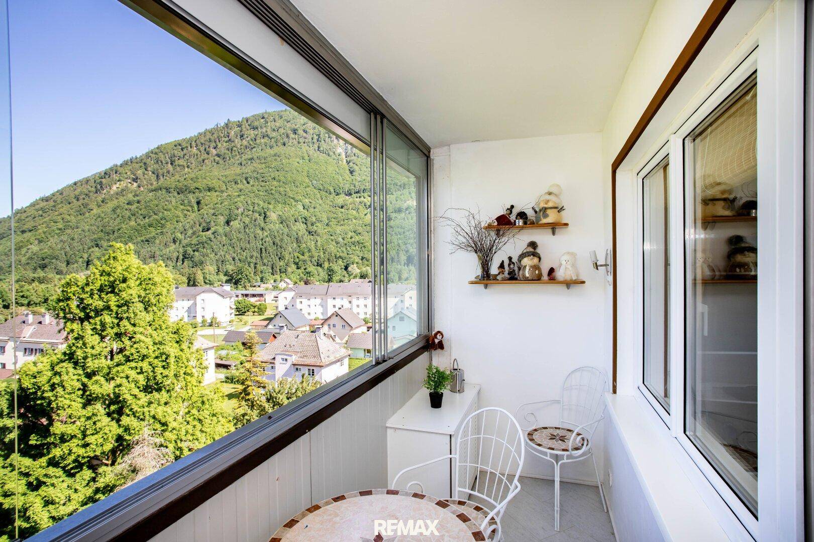 Verglaste Loggia mit Sitzgelegenheiten und Panoramablick auf die Berge und die umliegende Landschaft.