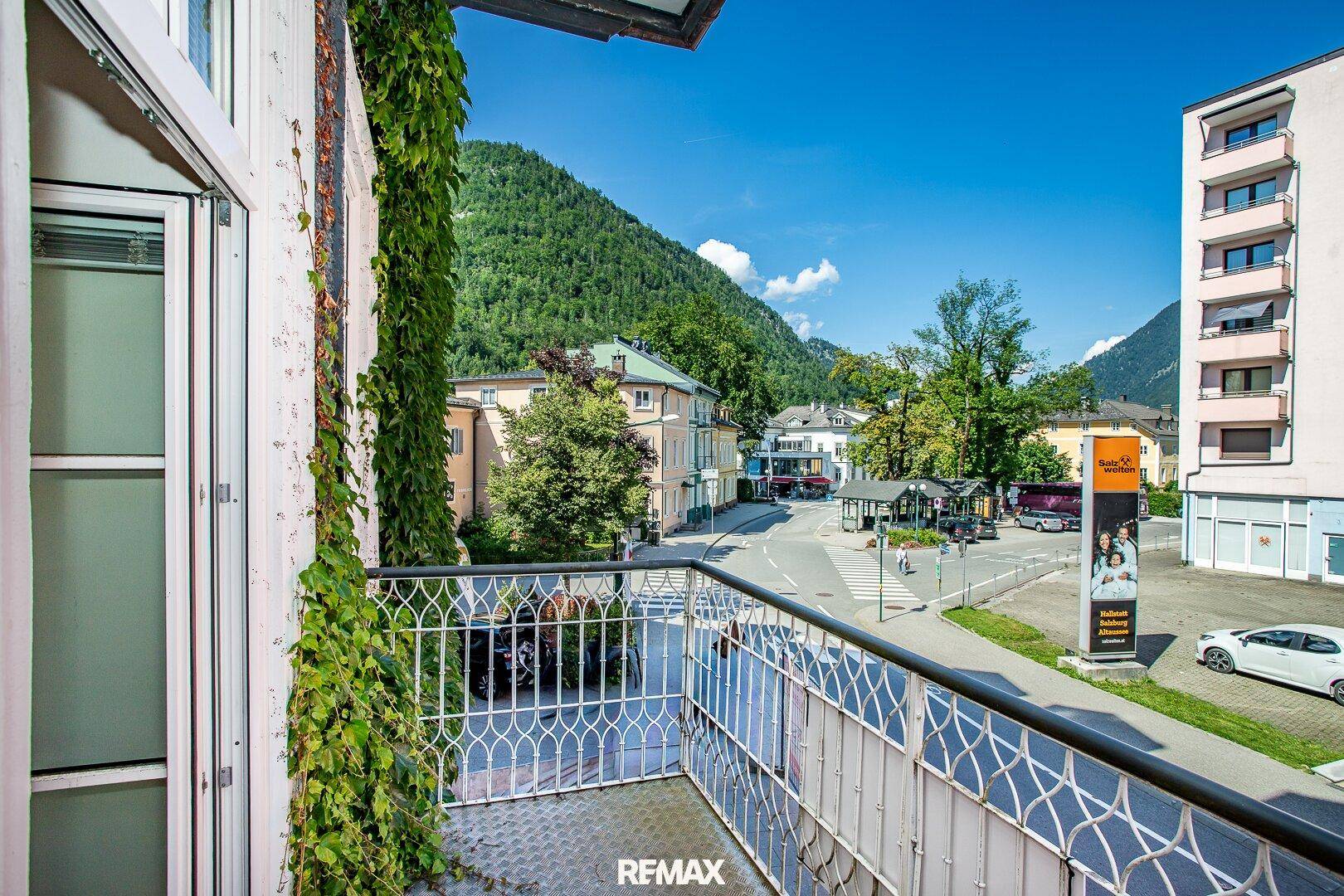 Balkon mit schmiedeeisernem Geländer und Blick auf eine belebte Straße und Berge.