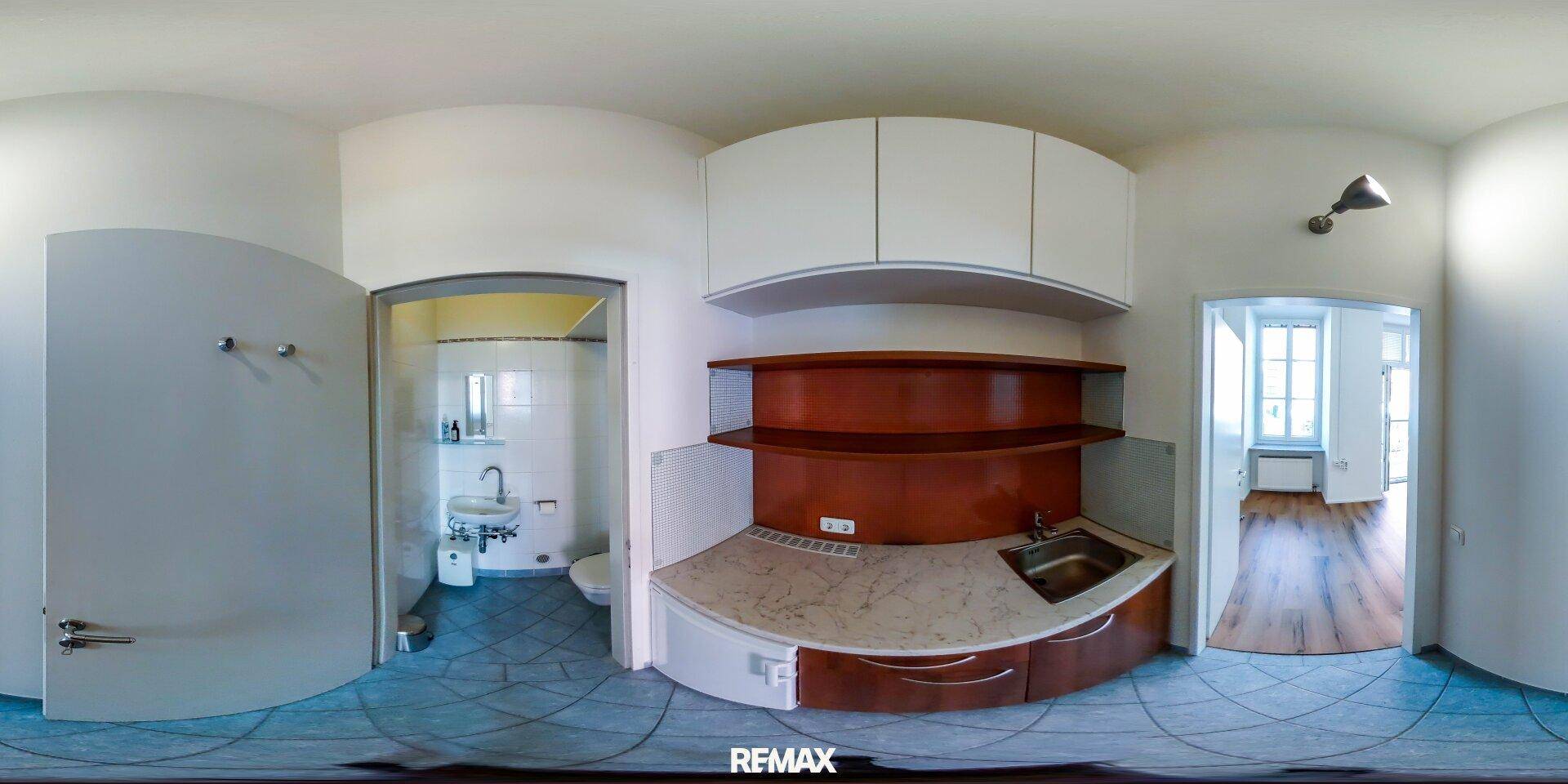 Panoramaansicht einer Teeküche mit Spüle und angrenzendem Badezimmer.