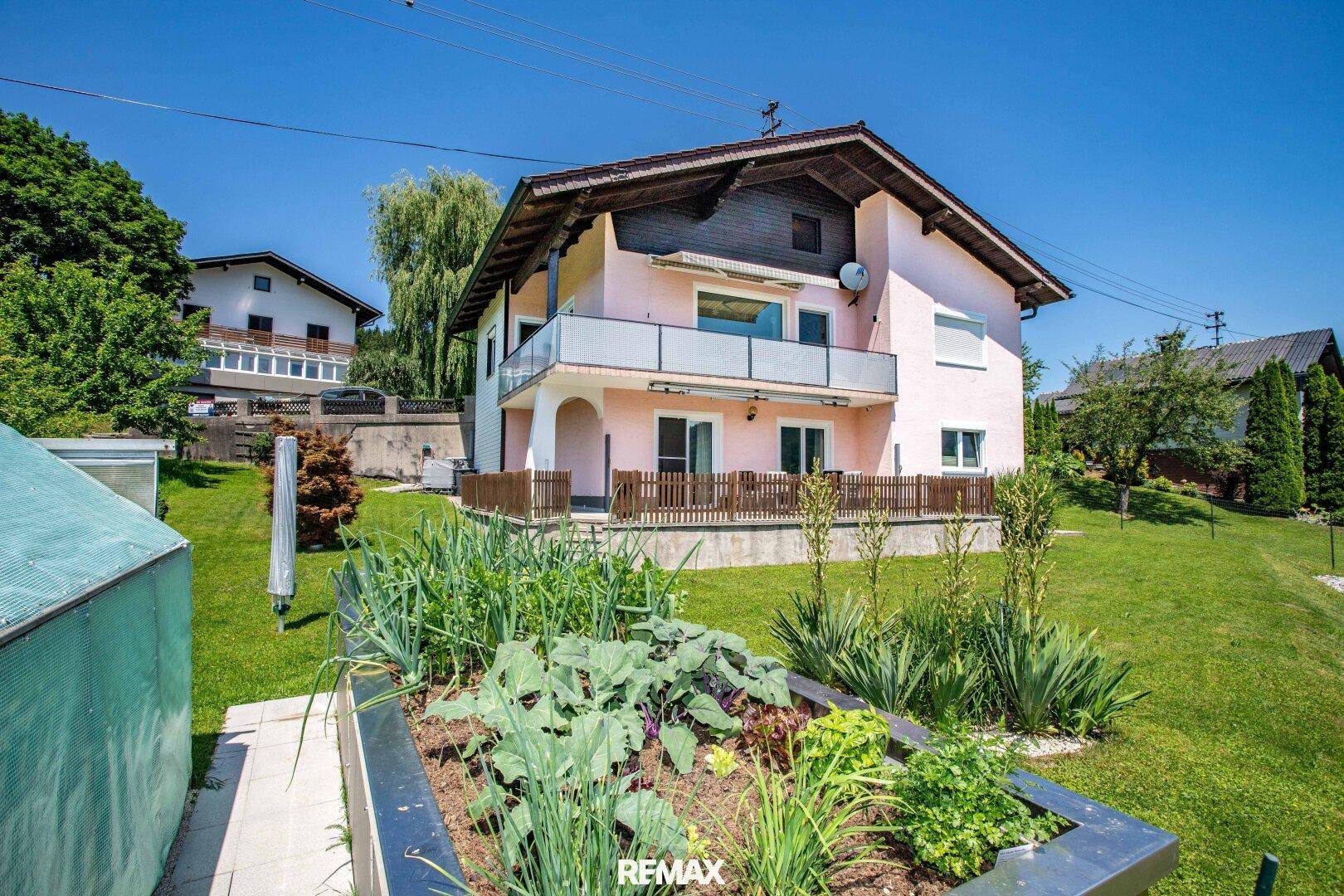 Außenansicht des Hauses mit gepflegtem Garten und einem Hochbeet im Vordergrund.