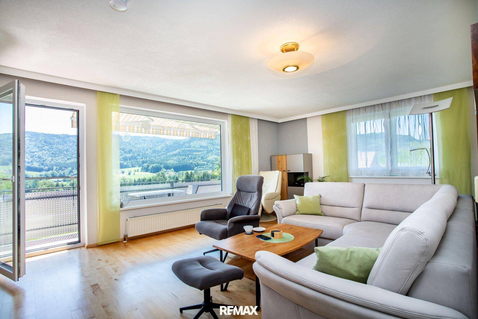 Gemütliches Wohnzimmer mit bequemer Sitzecke, Couchtisch und hellem Ausblick ins Grüne.