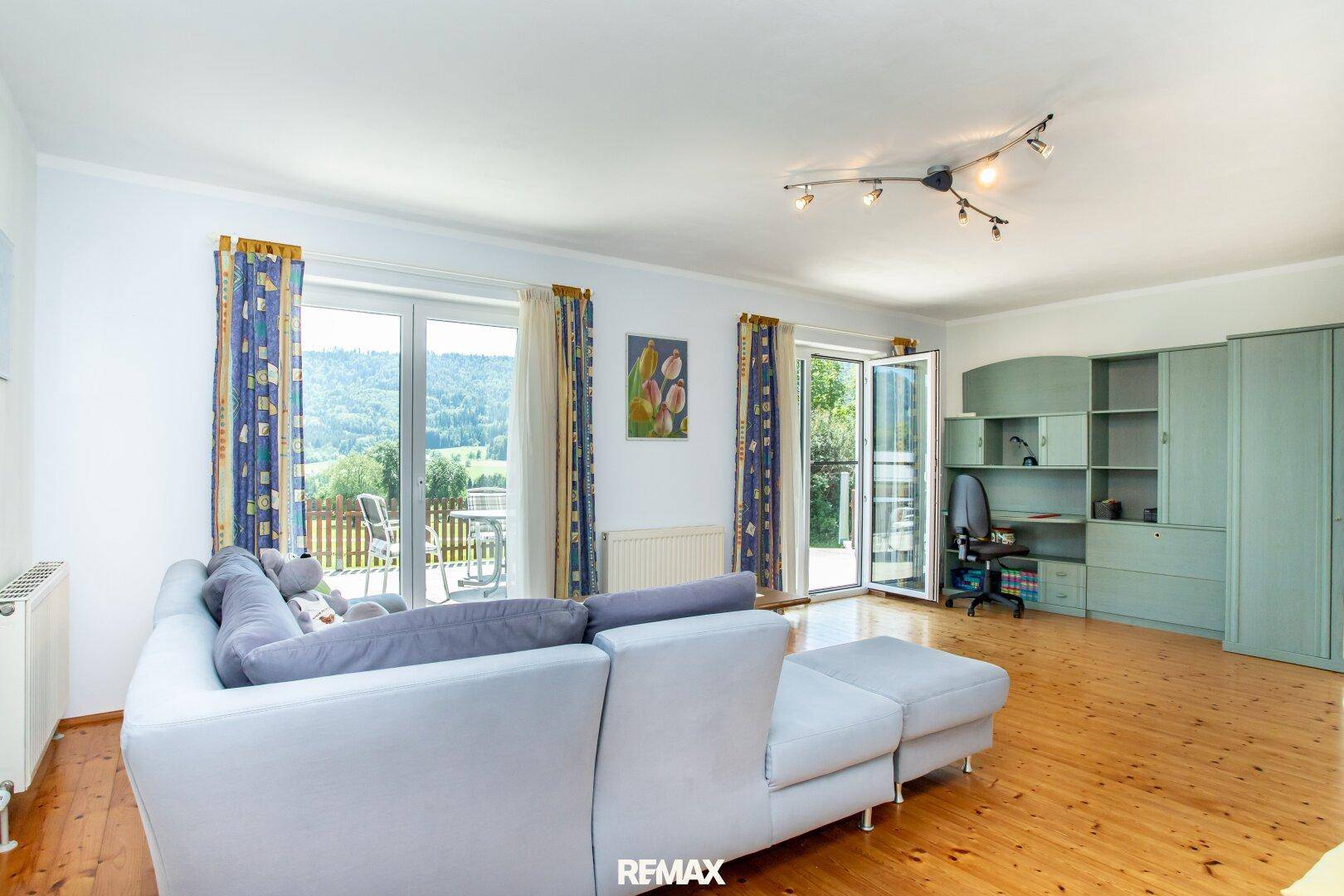 Geräumiges Wohnzimmer mit großem Sofa, Holzboden und direktem Zugang zur Terrasse.