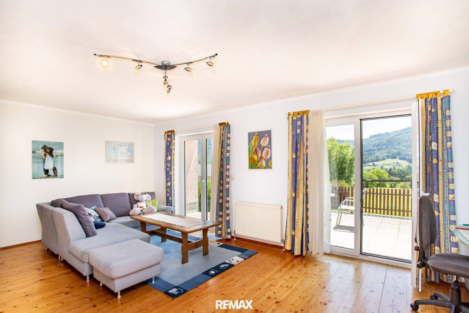 Helles Wohnzimmer mit bequemer Sitzecke, Holzboden und Zugang zu einem Außenbereich.