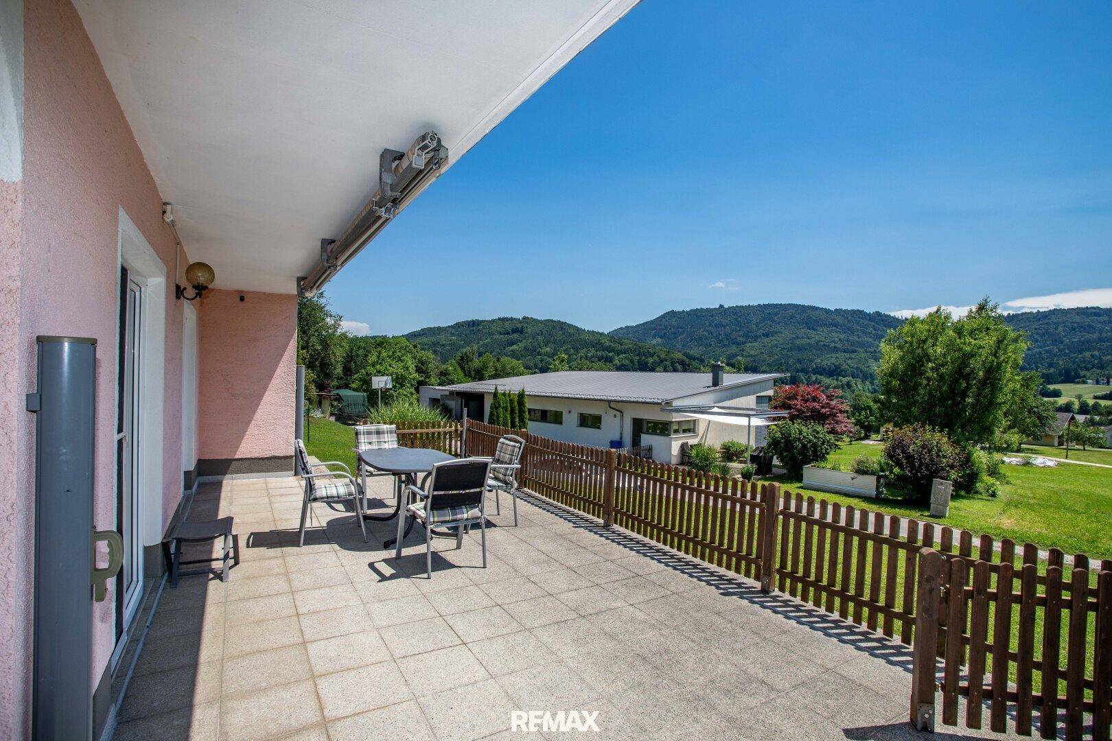 Geräumige Terrasse mit Gartenmöbeln, gefliestem Boden und Blick auf die Umgebung.