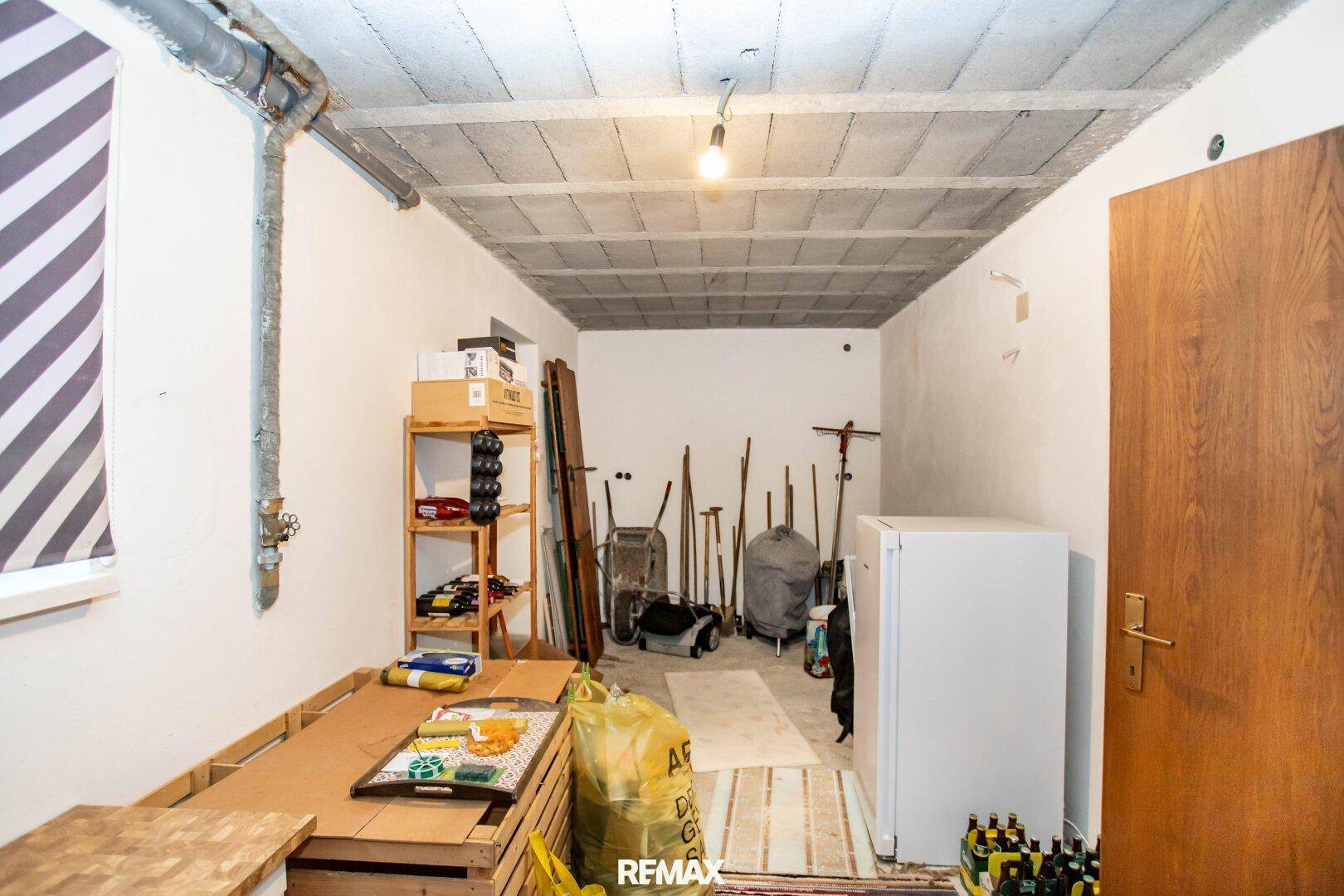 Praktischer Abstellraum im Keller mit Regalen, Lagerflächen und einem Kühlschrank.
