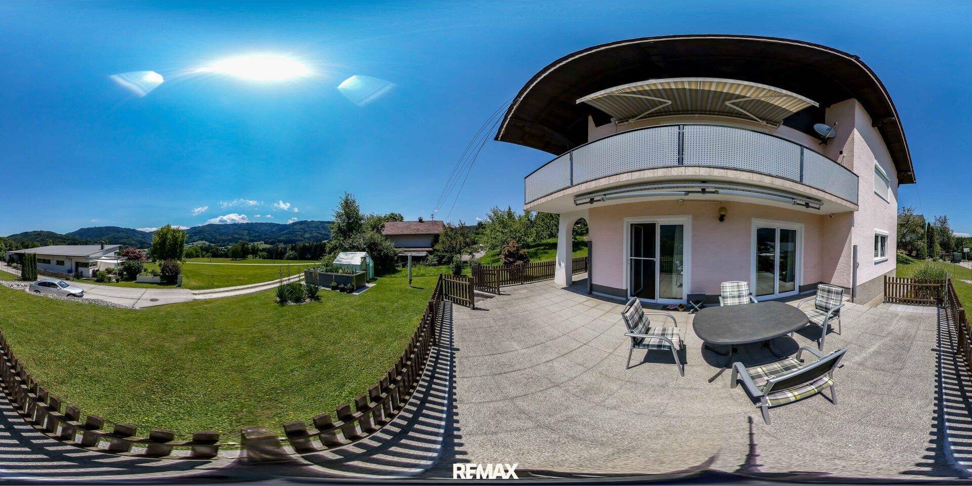 Große gepflasterte Terrasse mit Gartenmöbeln und weitem Blick ins Grüne.