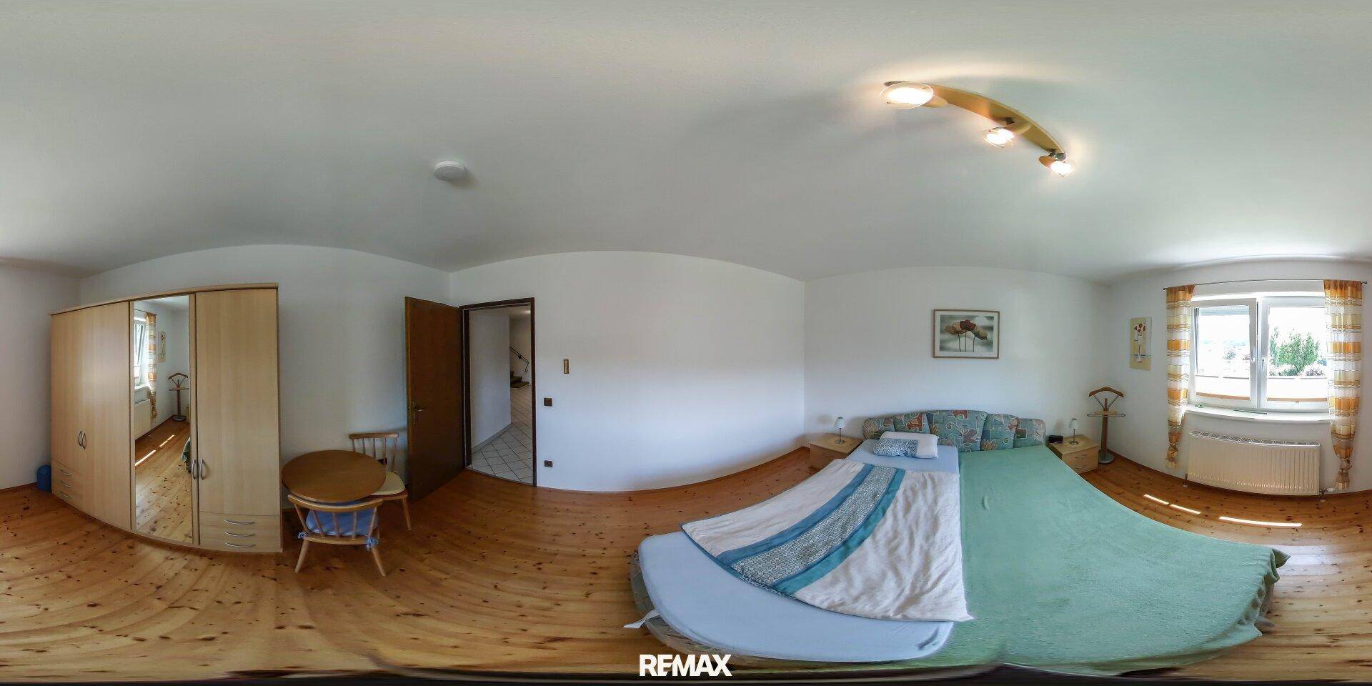 Geräumiges Schlafzimmer mit Holzboden, großem Bett und Kleiderschrank.