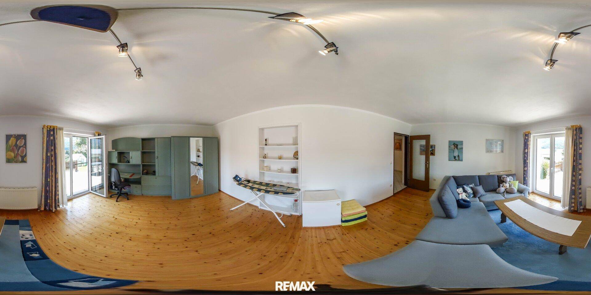 Helles Wohnzimmer mit Holzboden, Sofa und Zugang zu einem Balkon.