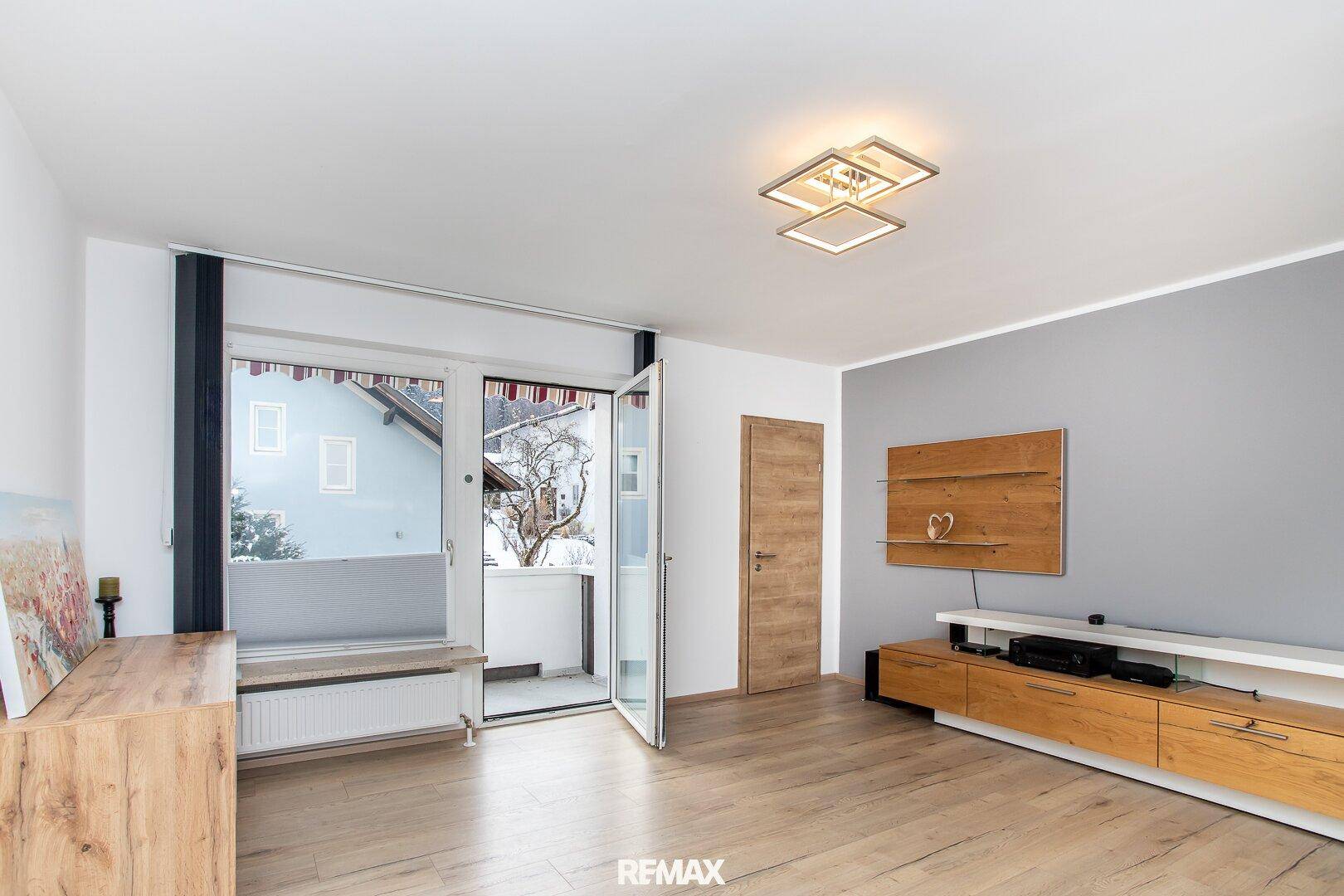 Helles Wohnzimmer mit modernem Design, Holzboden und direktem Zugang zum Balkon.
