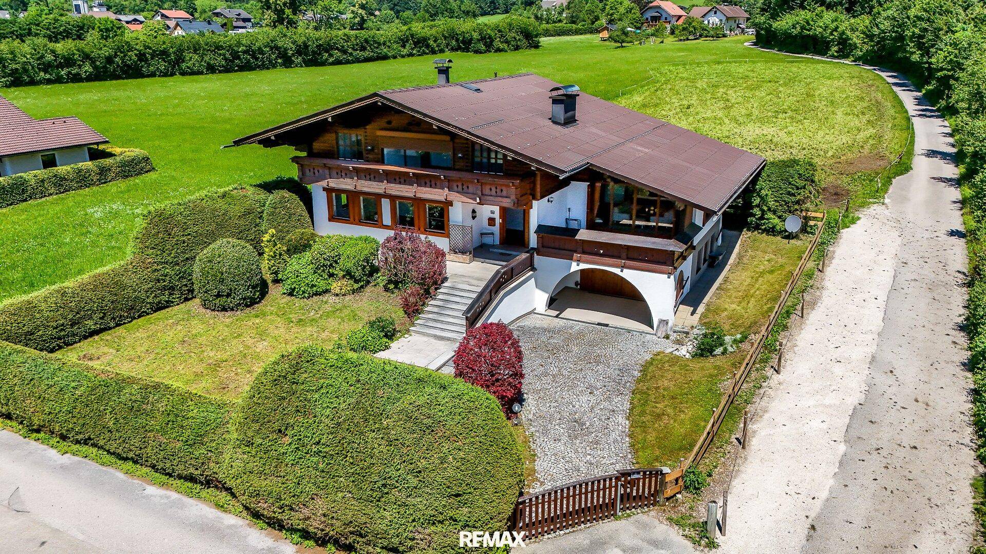 Vogelperspektive des Chalet-Hauses, umgeben von weitläufigen grünen Feldern und Natur.