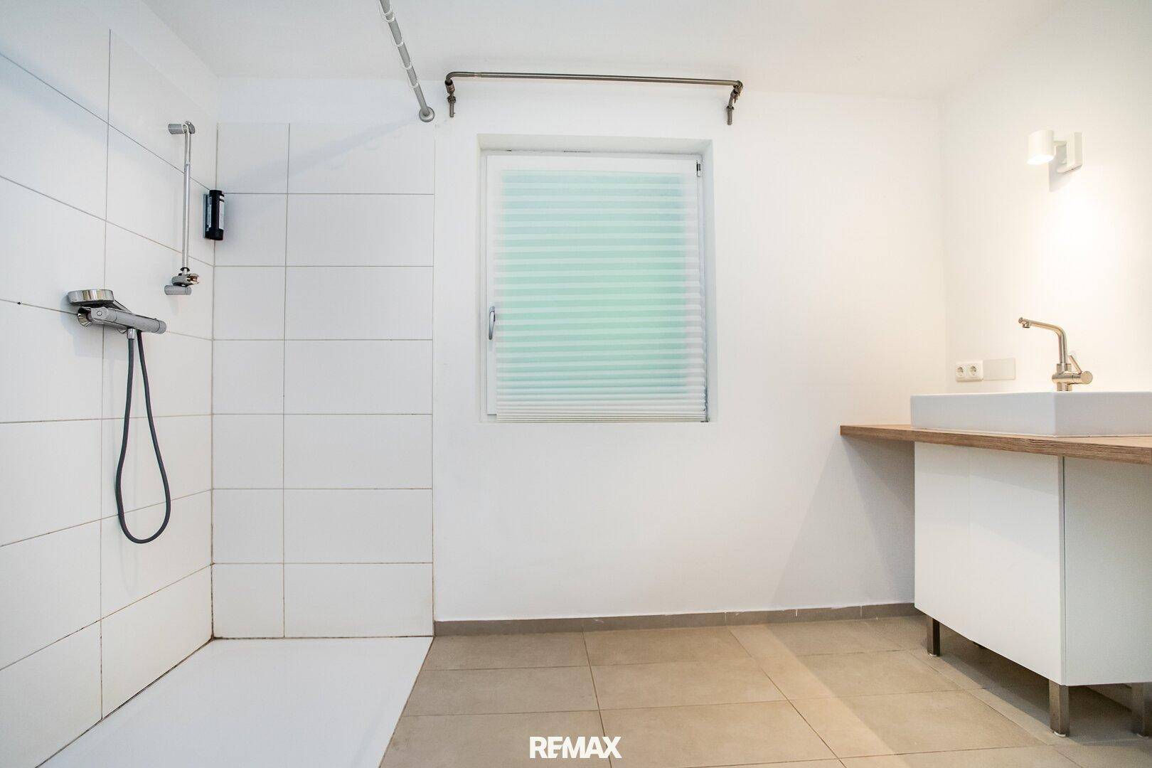 Modernes Badezimmer mit begehbarer Dusche, Waschbecken und Fenster für natürliches Licht.