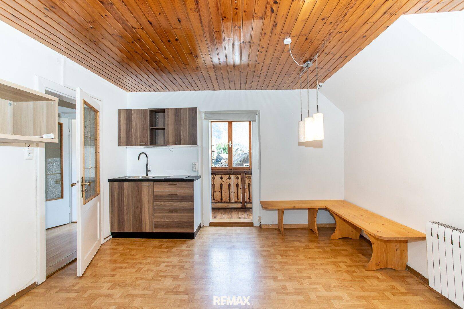 Offene Küchenzeile mit Holzboden und Zugang zu einem kleinen Balkon, ideal für Mahlzeiten.
