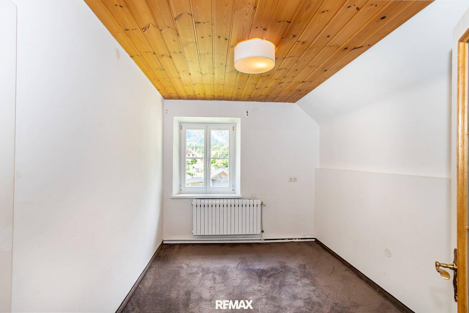 Gemütliches Schlafzimmer mit Holzboden und Holzdecke, einem Fenster und viel natürlichem Licht.