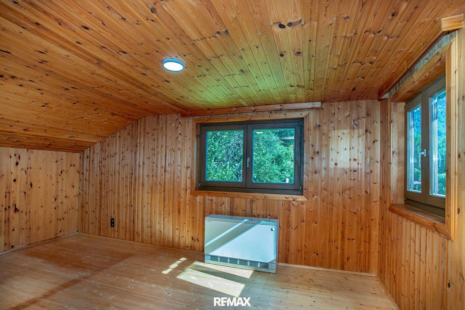 Gemütliches Zimmer mit vollständiger Holzvertäfelung an Wänden und Decke sowie Holzboden.