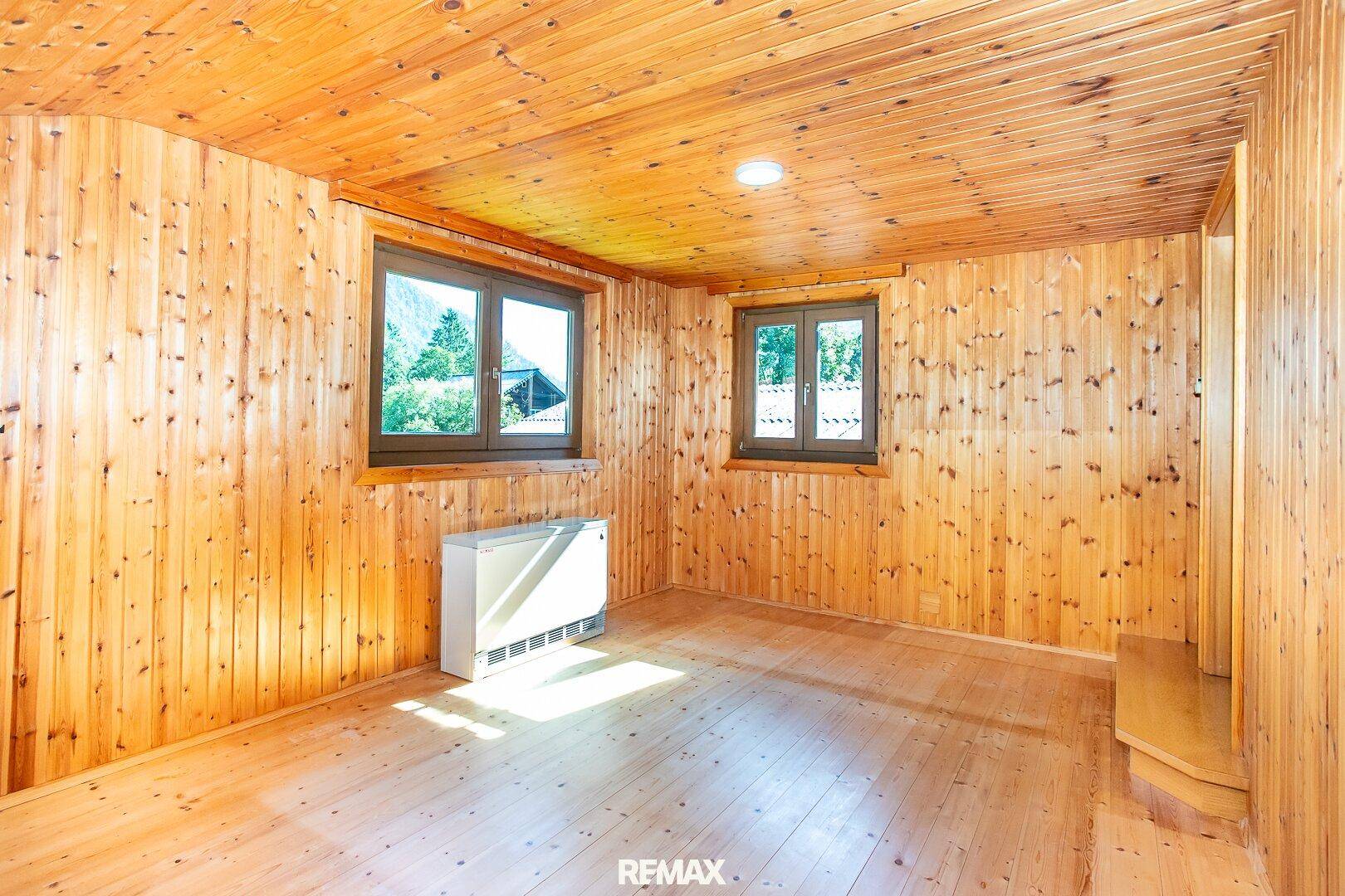 Helles Zimmer mit Holzboden und Holzvertäfelung, das eine warme und rustikale Atmosphäre schafft.