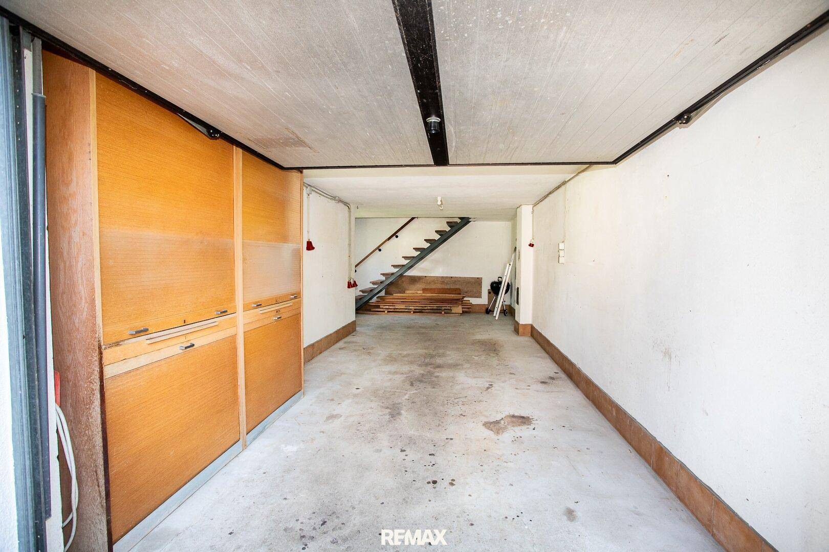 Geräumige Garage mit Betonboden und Stauraum, die direkten Zugang zum Haus bietet.