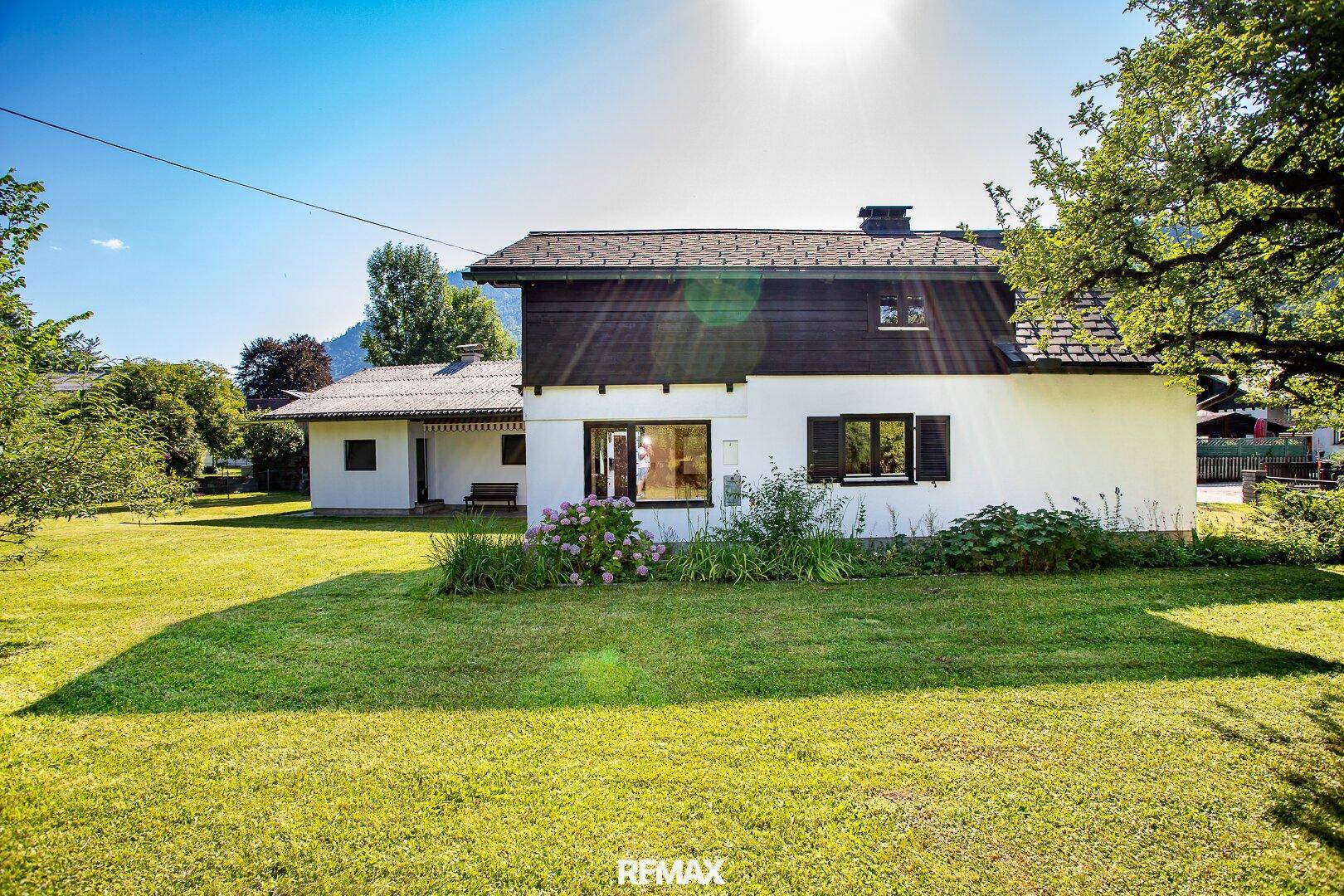 Rückansicht des Hauses mit großem, sonnigem Garten und gepflegter Rasenfläche.