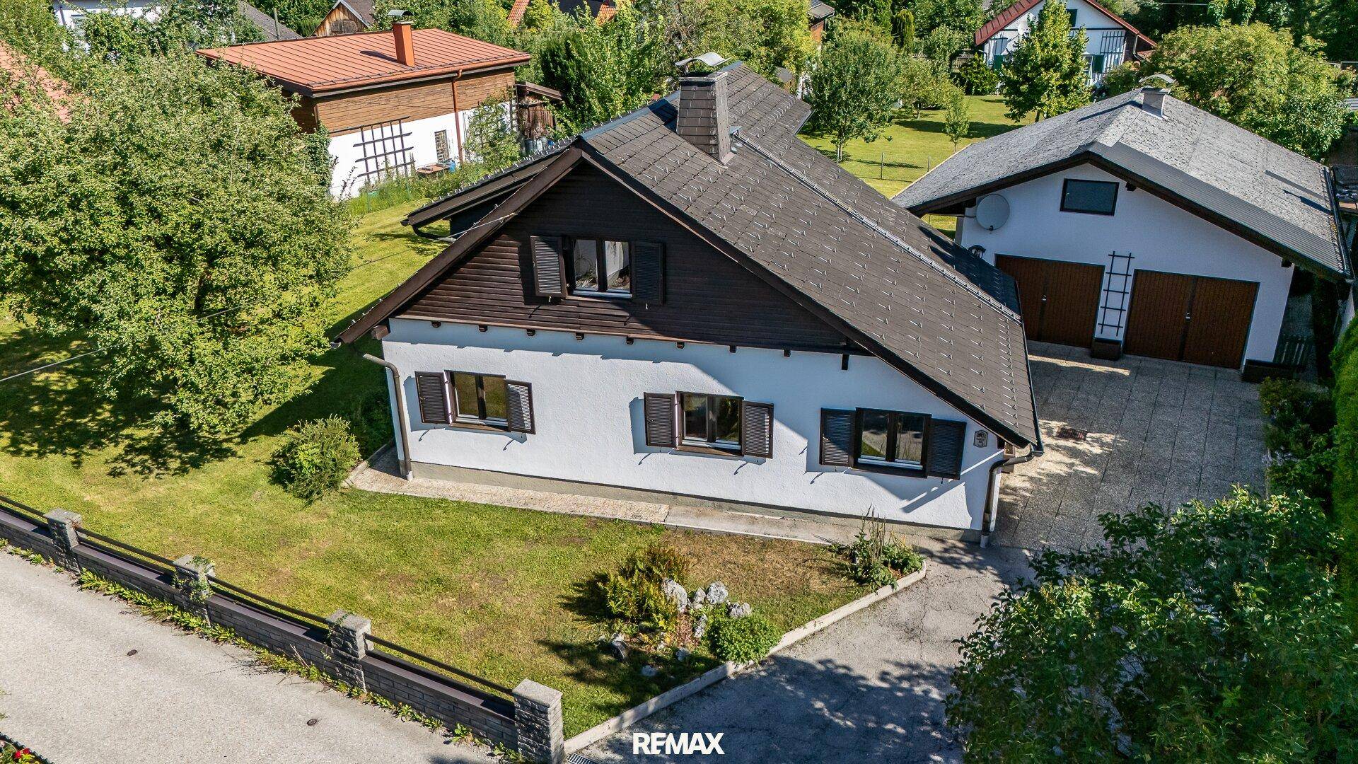 Luftaufnahme des traditionellen Hauses mit Garten, Garage und Zufahrt in ländlicher Umgebung.