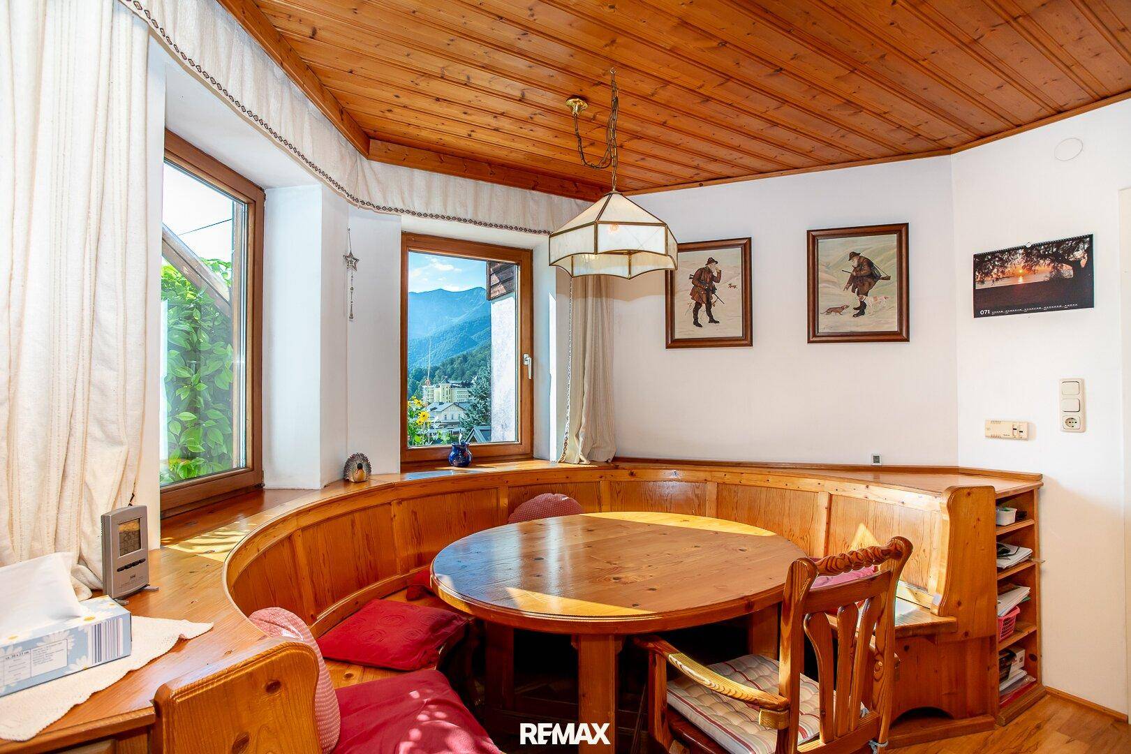Traditioneller Essbereich mit Eckbank, Holztisch und Fenstern mit Bergblick.