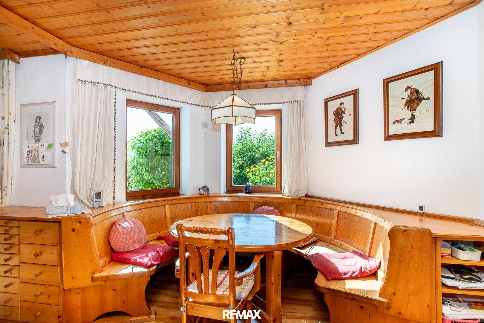 Heller Essbereich mit rustikaler Holzeckbank, Esstisch und Blick in den Garten.