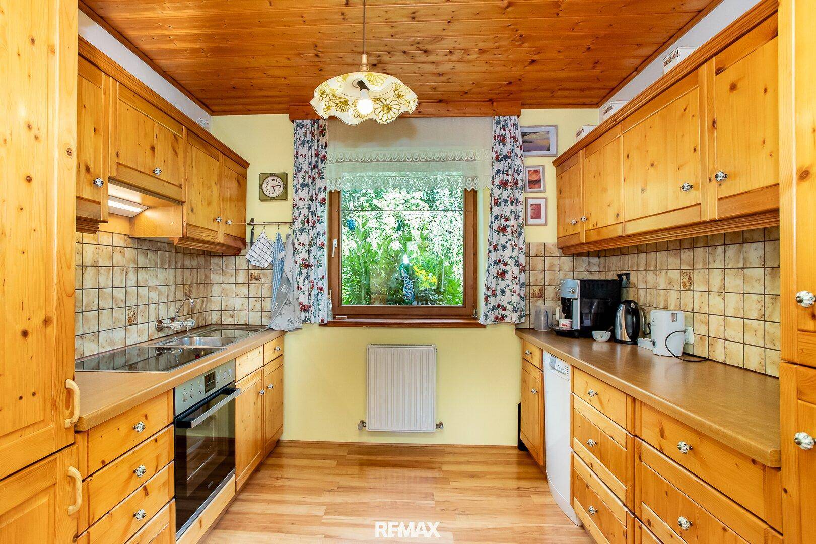 Funktionale Küche im Landhausstil mit Holzschränken, Fliesen und Gartenblick.