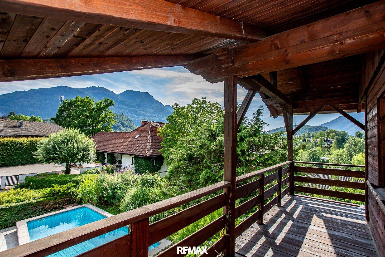 Geräumiger Holzbalkon mit Blick auf den Pool und die Berge.