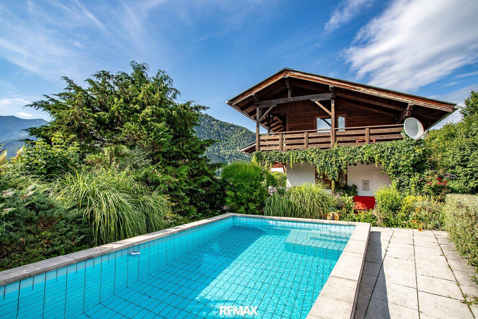 Einladender Außenbereich mit Pool, umgeben von üppigem Grün und Bergblick.